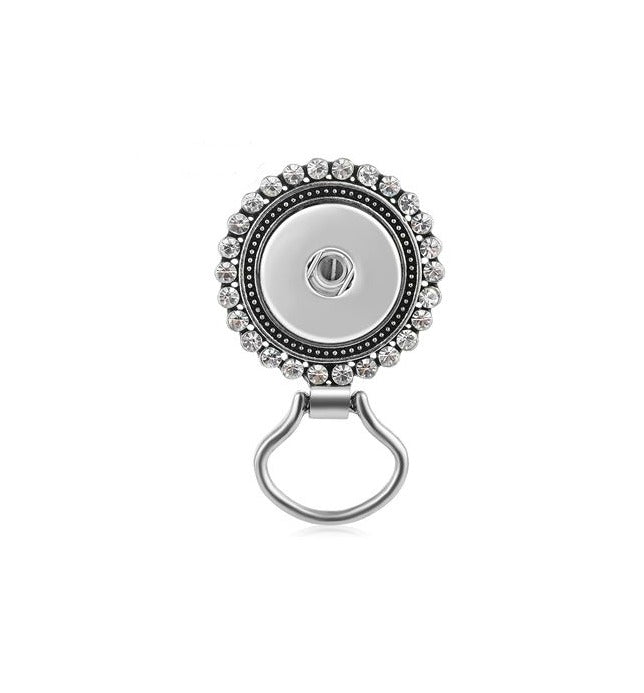 Round metal badge holder with decorative border on a white background