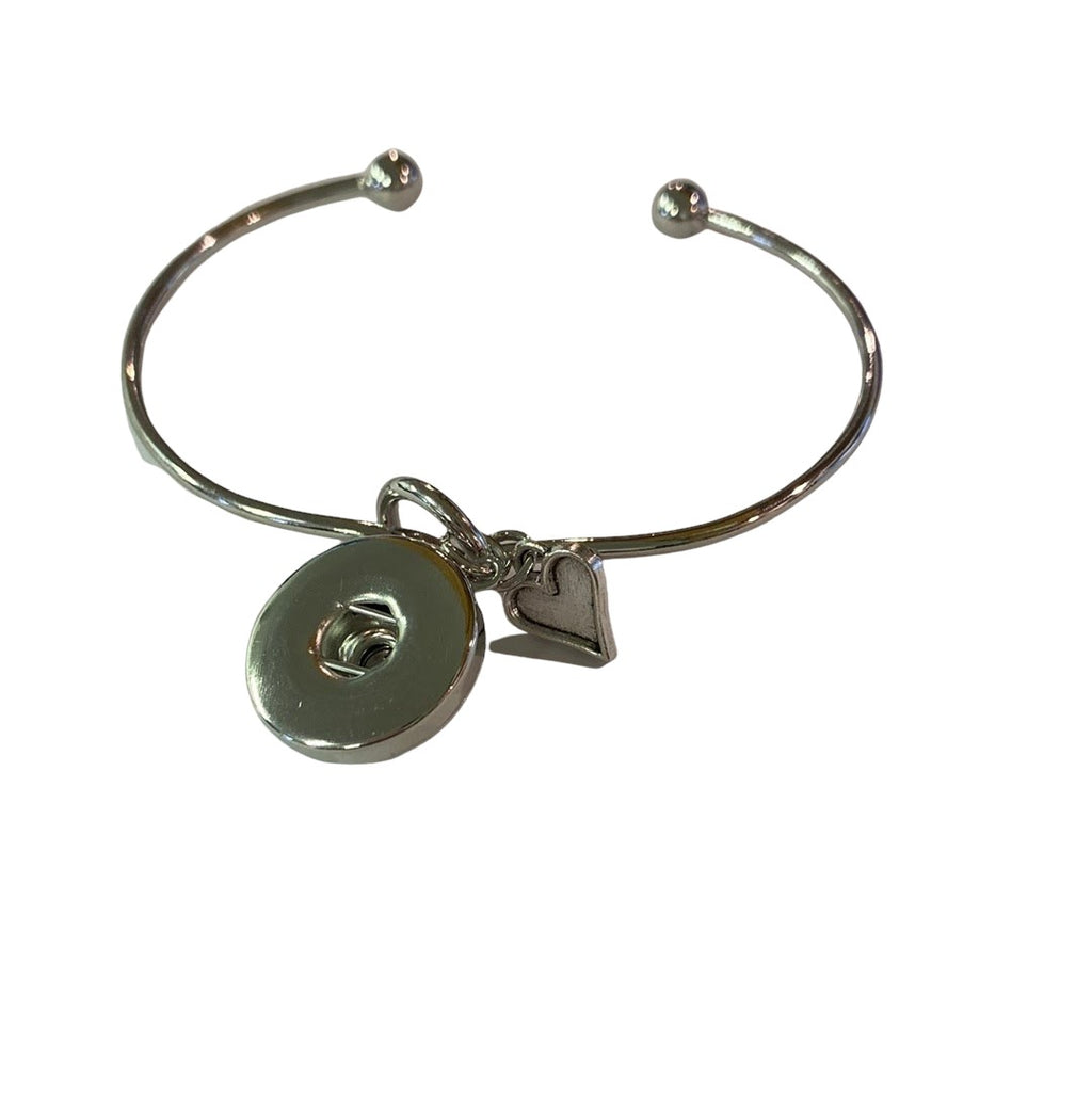 Simple Elegance Jewelry silver bangle bracelet featuring a 20mm snap charm and a dangling heart charm.